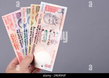 Altes indisches Geld - Rupie in der Hand auf grauem Hintergrund Stockfoto