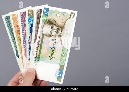 Old Myanmar Money - Kyat in der Hand auf grauem Hintergrund Stockfoto