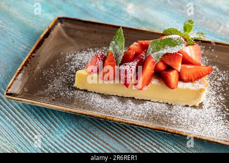 Ein Stück Käsekuchen mit Erdbeeren liegt auf einem Teller. Restaurant serviert Dessert Stockfoto