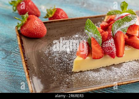 Ein Stück Käsekuchen mit Erdbeeren liegt auf einem Teller. Restaurant serviert Dessert Stockfoto
