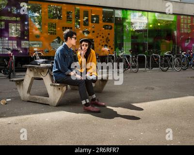 Zwei Studenten machen eine Pause vom Studium vor dem London College of Communications in Elephant und Castle london Stockfoto