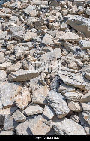 Feld aus gebrochenem Hardcore-Stein in hellem Sonnenlicht. Ich bin daran gewöhnt, verfallene Bauernhöfe zu flicken. Der größte Stein ist etwa 25cm. Auf steinigen Boden fallen Stockfoto