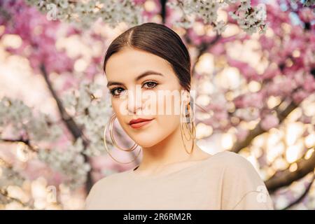 Außenporträt eines wunderschönen 18-20-jährigen Mädchens, das im blühenden Garten posiert Stockfoto