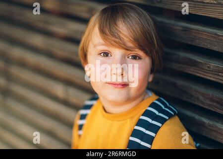 Außenporträt eines süßen Jungen mit gelbem Sweatshirt und Rucksack. Wieder-in-die-Schule-Konzept Stockfoto