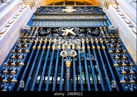 Valencia, Spanien - 15. Juli 2022: Schmiedeeiserner Eingang eines Gebäudes mit niedrigem Blickwinkel. Eine Glastür befindet sich hinter dem Metalleingang. Stockfoto