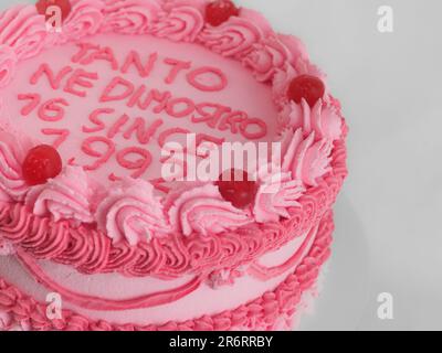 Rosafarbener, süßfroster Tassentorte mit italienischem englischem Schriftzeichen als Aufdruck für Bithday. Spaßiges Altern. Humorvolles Speisekonzept. Stockfoto