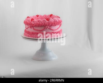 Rosafarbener, süßfroster Tassentorte mit italienischem englischem Schriftzeichen als Aufdruck für Bithday. Spaßiges Altern. Humorvolles Speisekonzept. Stockfoto