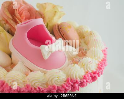Pinkfarbene Babyschuhe Kuchenauflage mit „Boy or Girl“-Schild für das Geschlecht der Babydusche enthüllt Milchglasscheiben mit zilindrischer Buttercreme. Stockfoto
