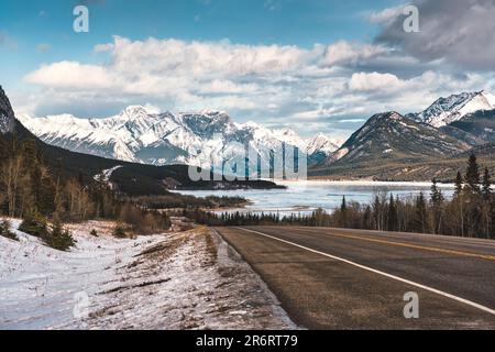 Malerische Landschaft auf der Highway Road mit felsigen Bergen und gefrorenem See am Icefields Parkway, Alberta, Kanada Stockfoto