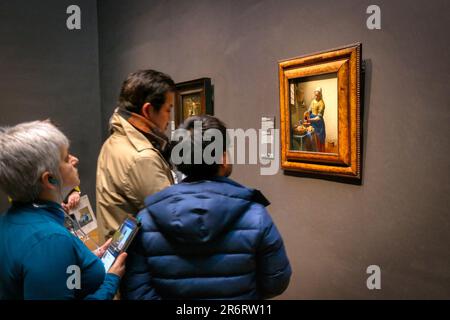 Besucher im Rijksmuseum, Amsterdam, mit Blick auf Vermeers Gemälde „die Milchfrau“ Stockfoto