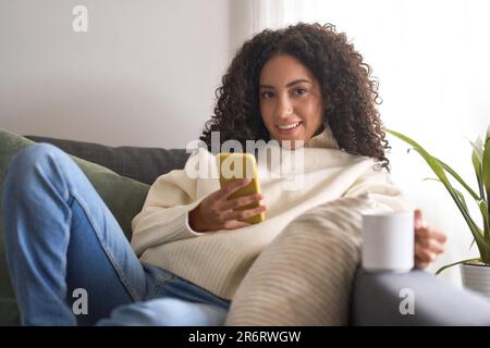 Junge hübsche Frau, die zu Hause mit dem Mobiltelefon telefonieren kann. Stockfoto