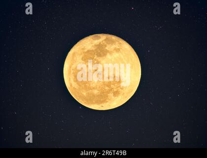 Phase des gelben Vollmondes mit einem strukturierten Krater, der mit Sternenhimmel am Nachthimmel glänzt Stockfoto
