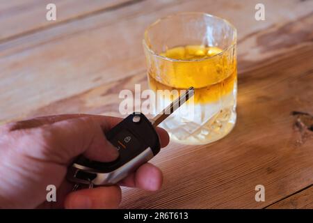 Glas mit Whiskey und Eis und Autoschlüssel auf Holzhintergrund. Trunkenheit am Steuer, Trunkenheitsrisiko am Steuer Stockfoto