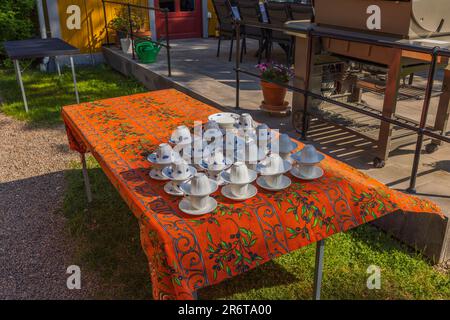 Blick auf Kaffeetassen, die für die Party auf der Terrasse am wunderschönen Sommertag zubereitet wurden. Schweden. Stockfoto