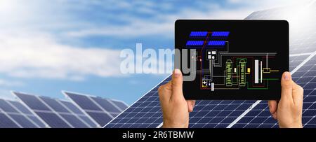 Installationsplan einer Solarenergiestation auf einem Bildschirm eines digitalen Tablets auf dem Hintergrund von Solarpaneelen. Stockfoto