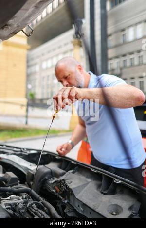 Leitender Mechaniker, der den Ölstand im Automotor überprüft. Stockfoto