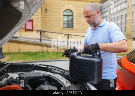 Der Mechaniker gießt Öl in den Motor. Frisches Öl in den Fahrzeugmotor gießen, Öl in Automatikgetriebe wechseln. Stockfoto