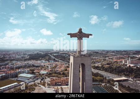 Die Drohne schwingt hoch und hält die Christusstatue und die berühmte rote Brücke in einer weitläufigen Landschaft fest. Eine harmonische Mischung aus Glauben und Ingenieurskunst Stockfoto