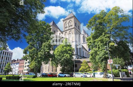 Köln (Köln), Deutschland - Juni 6. 2023: Wunderschöne romanische Architektur, mittelalterliche deutsche St. Kunibert-Kirche aus dem 12. Jahrhundert mit grünem Baumpark Stockfoto