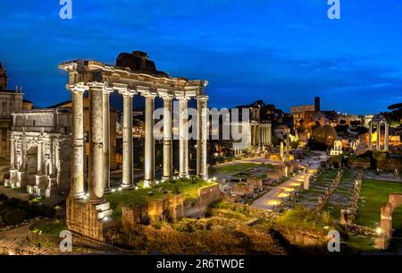 Das Forum Romanum beleuchtet bei Nacht mit den Ruinen des Saturn-Tempels im Vordergrund, Rom, Italien Stockfoto