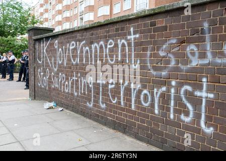 Knightsbridge, London, Großbritannien. 11. Juni 2023. Demonstranten versammelten sich vor der Botschaft der Islamischen Republik Iran in London und protestierten zugunsten des kurdischen Volkes, was eine umfassende Reaktion der Polizei veranlasste. Polizeibeamte schützen die Botschaft. Graffiti an der Wand, dass die britische Regierung den Terrorismus nicht mehr unterstützt Stockfoto