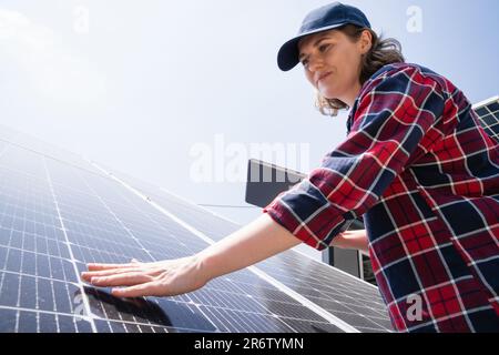 Frau mit digitalem Tablet, die das Solarmodul berührt Stockfoto