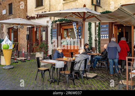 Leute sitzen vor dem Tiberino Ristorante, einem kleinen familiengeführten italienischen Restaurant auf Tiber Island, Rom, Italien Stockfoto