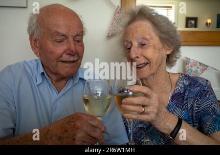 Ein älteres Ehepaar, das beide über 90s Jahre alt ist, trinkt nach 70 Jahren Ehe mit Wein. Stockfoto