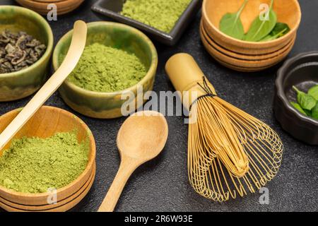 Bambusschläger und Messlöffel. Matcha Grüntee-Pulver in der Schüssel. Schließen. Schwarzer Hintergrund Stockfoto