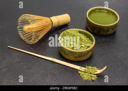 Schüssel Matcha-Pulver und Schüssel Matcha-Tee. Bambusschläger und Messlöffel. Schließen. Schwarzer Hintergrund Stockfoto