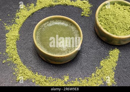 Schüssel Matcha-Pulver und Schüssel Matcha-Tee. Matcha-Pulver auf dem Tisch. Draufsicht. Schwarzer Hintergrund Stockfoto