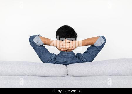 Entspannter Mann, der zu Hause auf der Couch ruht, Rückansicht Stockfoto