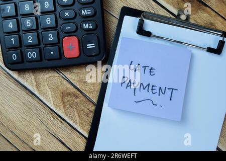 Konzept des Schreibens von Zahlungsverzug auf Haftnotizen, die auf einem Holztisch isoliert sind. Stockfoto