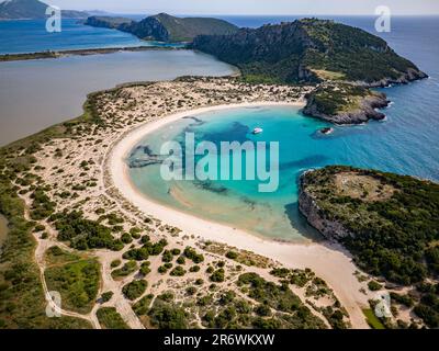 Blick auf den Strand von Voidokilia auf dem Peloponnes in Messinien/Griechenland mit klarem blauem Wasser und Katamaran-Segelboot in der Bucht Stockfoto