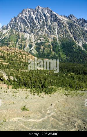 Männliche Wanderer kämpfen bergauf mit Mount Stuart dahinter, Cascades Range, Washington Stockfoto