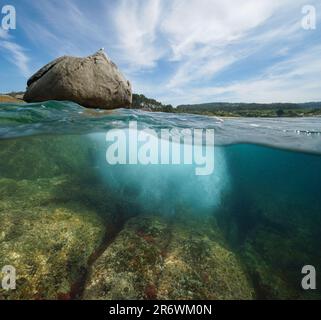 Boulder am Meer mit Felsen unter Wasser, geteilter Blick über und unter der Wasseroberfläche, Atlantikküste in Spanien, Galicien, Rias Baixas Stockfoto