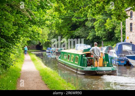 Kanal-Narrowboat durch das Dorf Govilon in Südwales am ruhigen Monmouth und Brecon Kanal Stockfoto