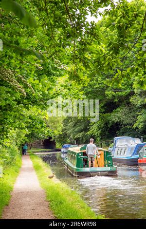 Kanal-Narrowboat durch das Dorf Govilon in Südwales am ruhigen Monmouth und Brecon Kanal Stockfoto