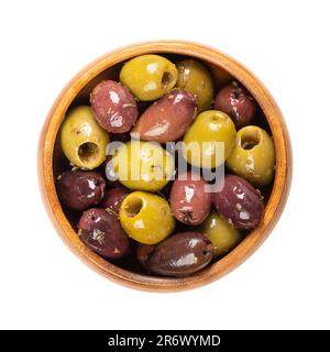 Entsteinte Kalamata und grüne Oliven, in einer Holzschüssel. Mischung aus griechischen Bio-Oliven, grün und schwarz, mit Kräutern, die in nativem Olivenöl konserviert werden. Stockfoto