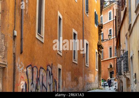 Eine Frau, die in Rom, Italien, entlang einer engen Straße spaziert Stockfoto