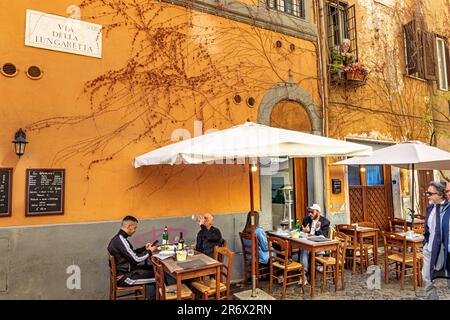 Leute sitzen an Tischen vor einem Restaurant in Trastevere, Rom, Italien Stockfoto