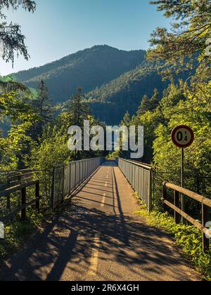 Brücke auf dem Alpe-Adria-Fahrrad eurovelo Way in Tarvisio, Italien während der Sommermonate goldene Stunde mit Bergen im Hintergrund, keine Menschen leer Stockfoto