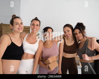 Eine Gruppe junger Frauen, Fitness-Freunde oder Yogis im Fitnessstudio oder Studio, die zusammen mit einer schwangeren Frau lachen Stockfoto