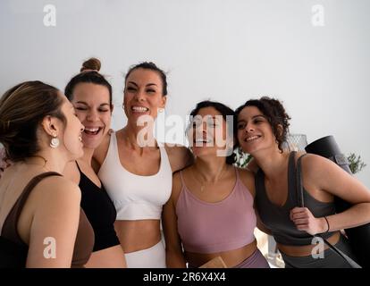 Eine Gruppe junger Frauen, die mit einer schwangeren Frau im Fitnessstudio oder Studio zusammen lachen Stockfoto