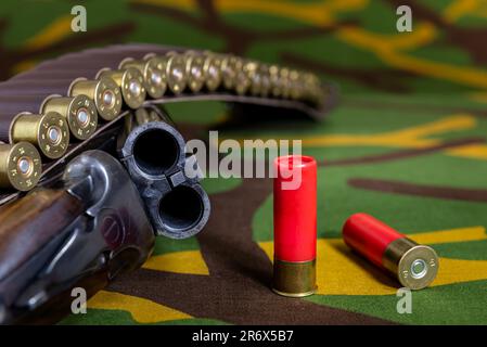 Jagdgewehr mit Munition auf Tarnhintergrund. Selektiver Fokus. Stockfoto