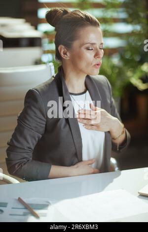 Nachhaltiger Arbeitsplatz. Entspannte, moderne Eigentümerin eines kleinen Unternehmens in einem modernen grünen Büro, die Atemübungen macht. Stockfoto