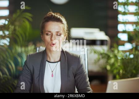 Nachhaltiger Arbeitsplatz. Entspannte, moderne Geschäftsfrau bei der Arbeit, die Atemübungen macht. Stockfoto