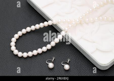 Elegante weiße Perlenkette und Ohrringe auf schwarzem Hintergrund Stockfoto