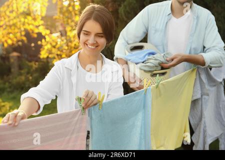 Glückliche Familie, die Kleidung aufhängt, mit Wäscheklammern an der Wäscheleine, um im Garten zu trocknen Stockfoto