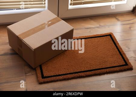 Paket auf der Matte nahe der Vordertür in Innenräumen Stockfoto